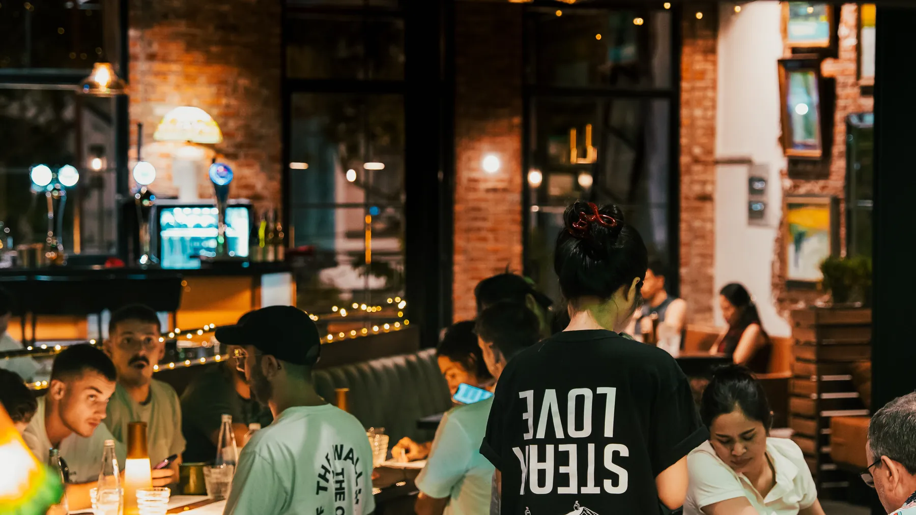 The dining room at Missteak Da Nang at night, guests at the tables and a server walking through in a Missteak tee